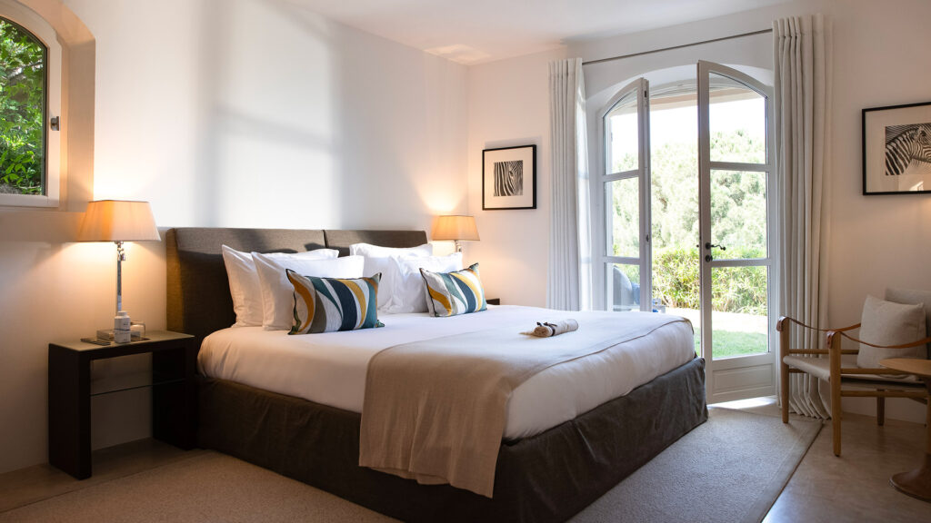 Chambre lumineuse à La Réserve Ramatuelle avec lit double, jeté de lit et ouverture sur terrasse