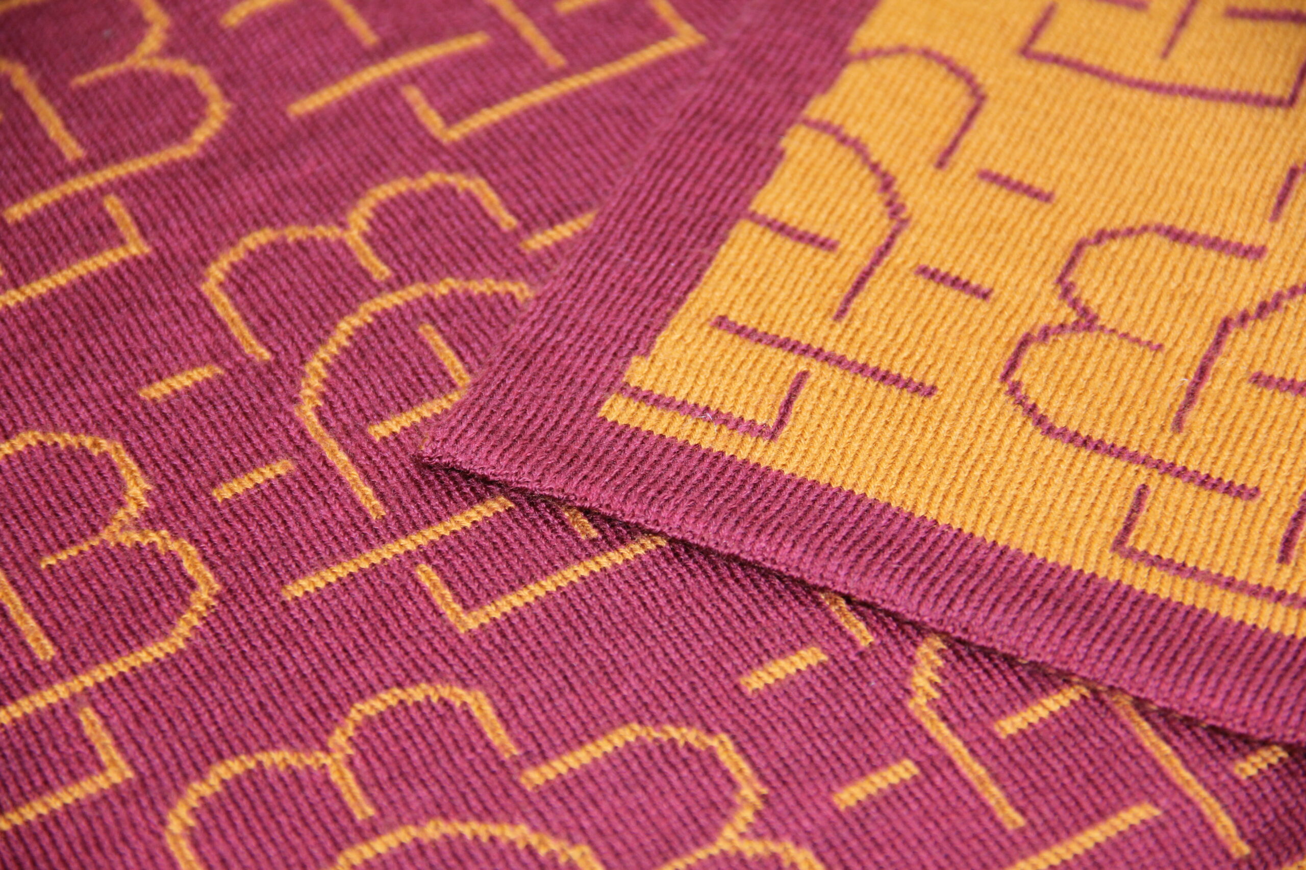 Détail de la texture et du motif d’un plaid en maille rouge et jaune réalisé sur mesure