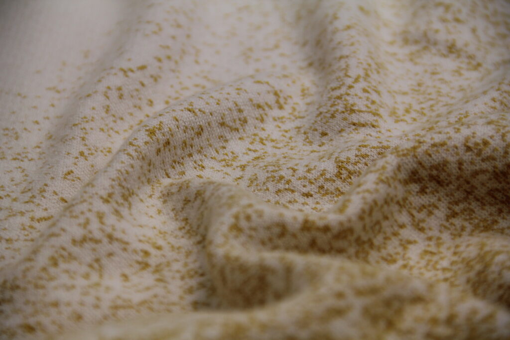Gros plan sur la maille d’un plaid en laine recyclée, texture textile